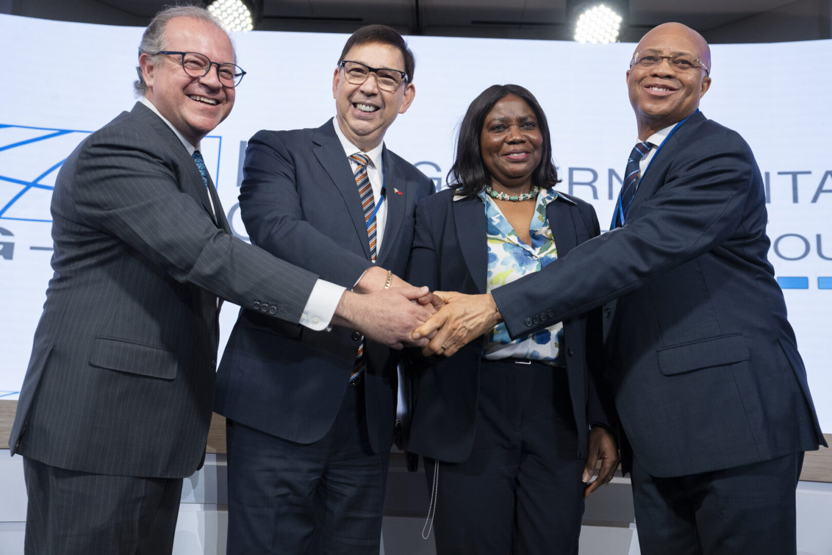 Four people shaking hands in suits.